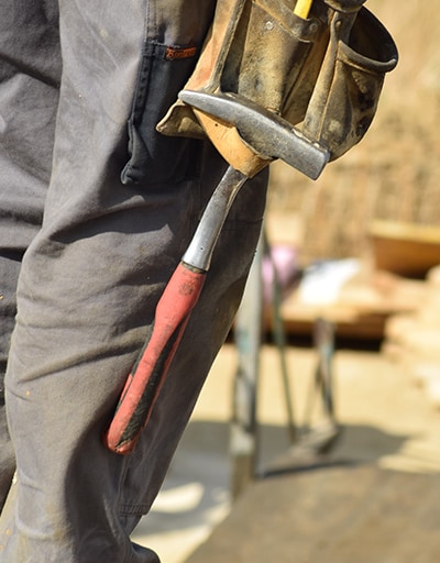 Nahaufnahme eines Hammers am Werkzeuggürtels eines Bauarbeiters